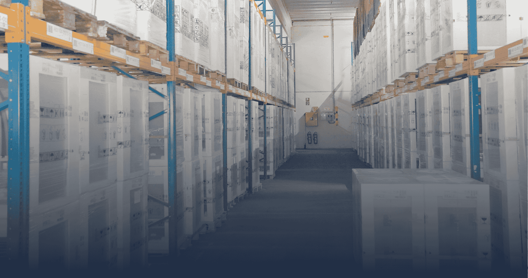 Zu sehen ist ein professionelles Hochregallager mit langen Regalreihen in blau-orange, auf denen beidseitig folienverpackte Paletten mit Retouren und B-Ware systematisch gelagert sind. Der breite Mittelgang ermöglicht Gabelstapler-Zugang für effiziente Warenlogistik im B2B-Retouren-Großhandel.