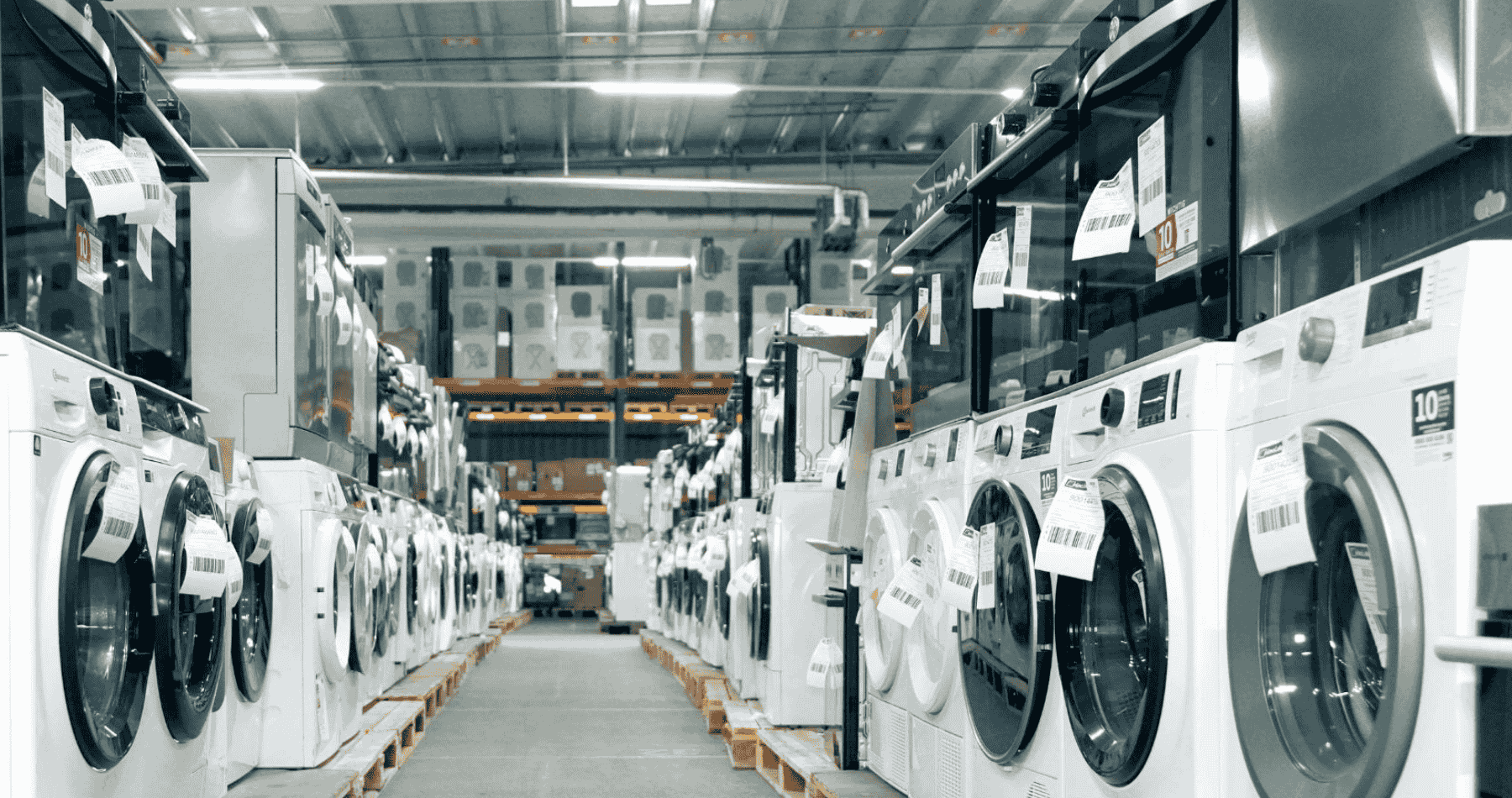 Beidseitige Reihen weißer Waschmaschinen-Retouren mit Etiketten im B2B-Großhandelslager für Elektrogeräte